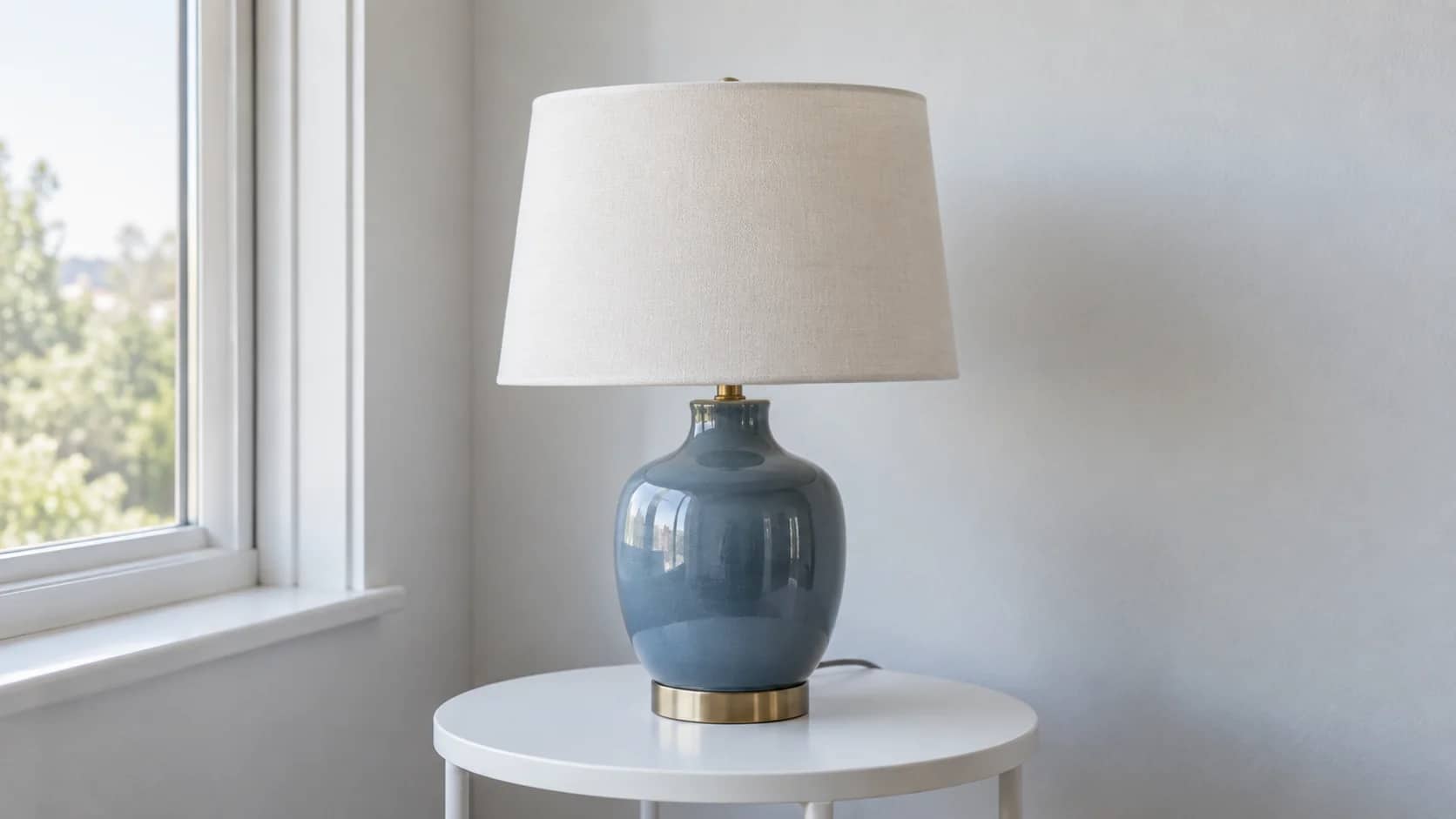 A blue ceramic table lamp with a fabric shade and a small brass base.